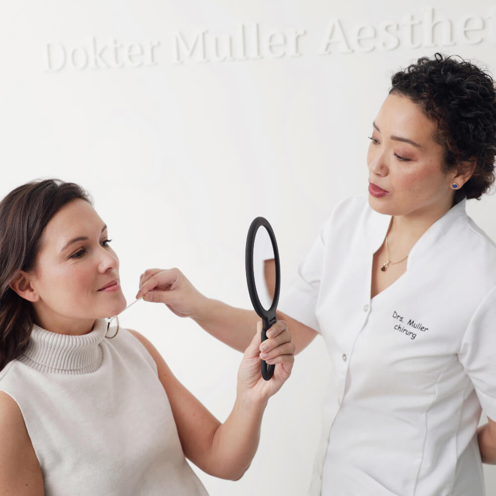 Dokter Muller laat een patiënt het resultaat zien in de handspiegel